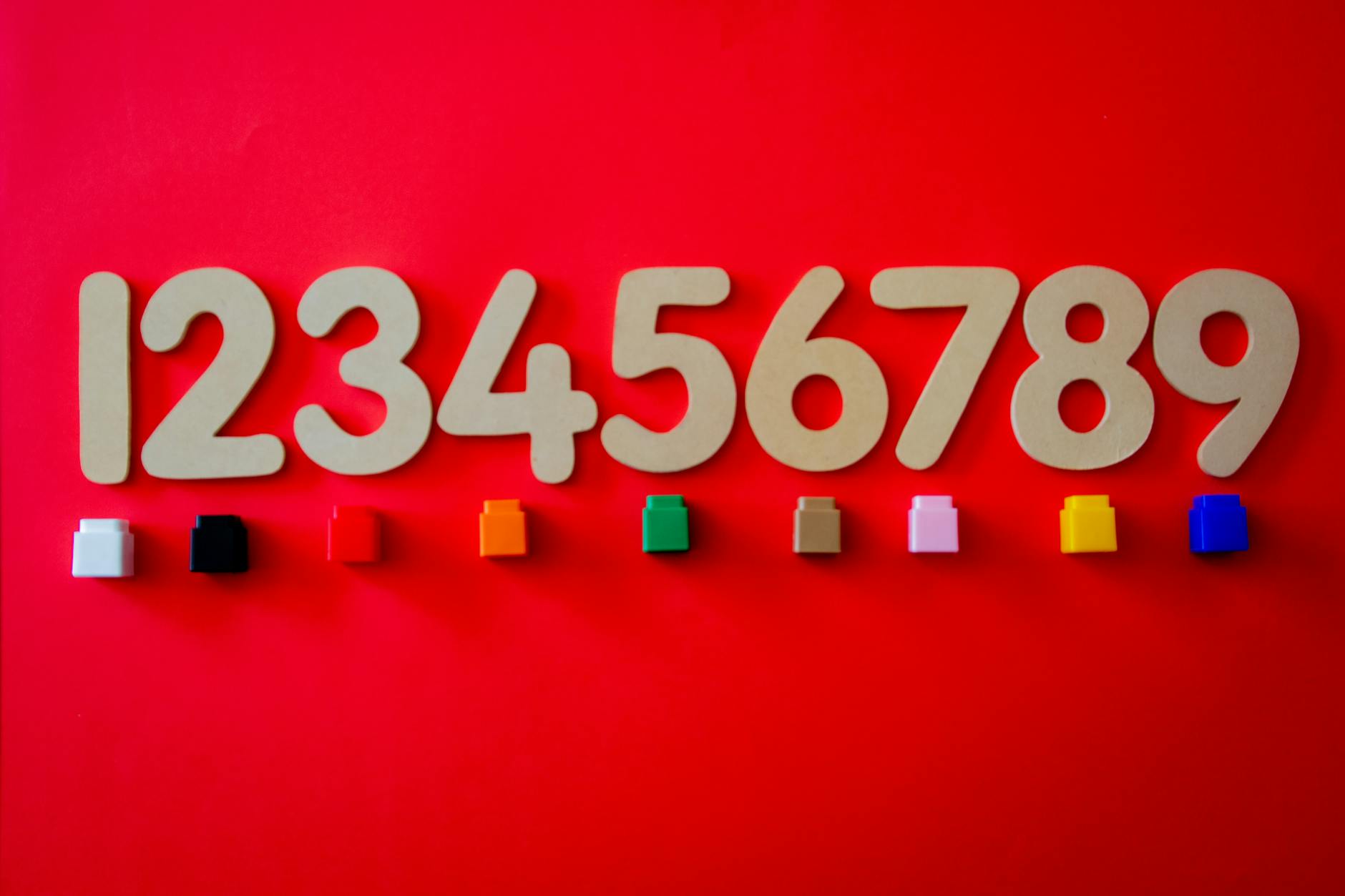 Wooden numbers 1 to 9 arranged with colorful small cubes on a red background