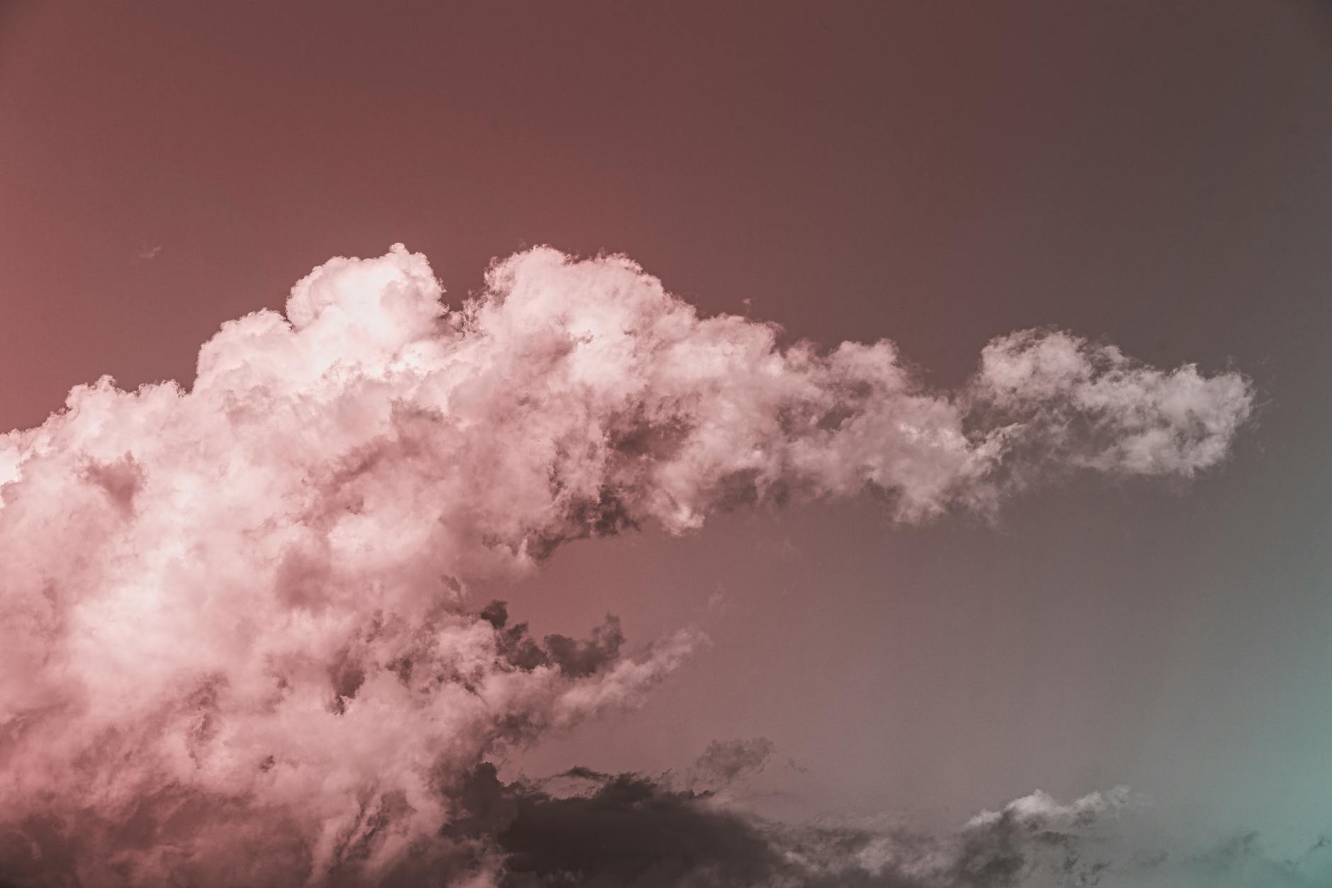 Roze getinte wolken in een zachte avondlucht bij zonsondergang tegen een rustige, gedempte hemel