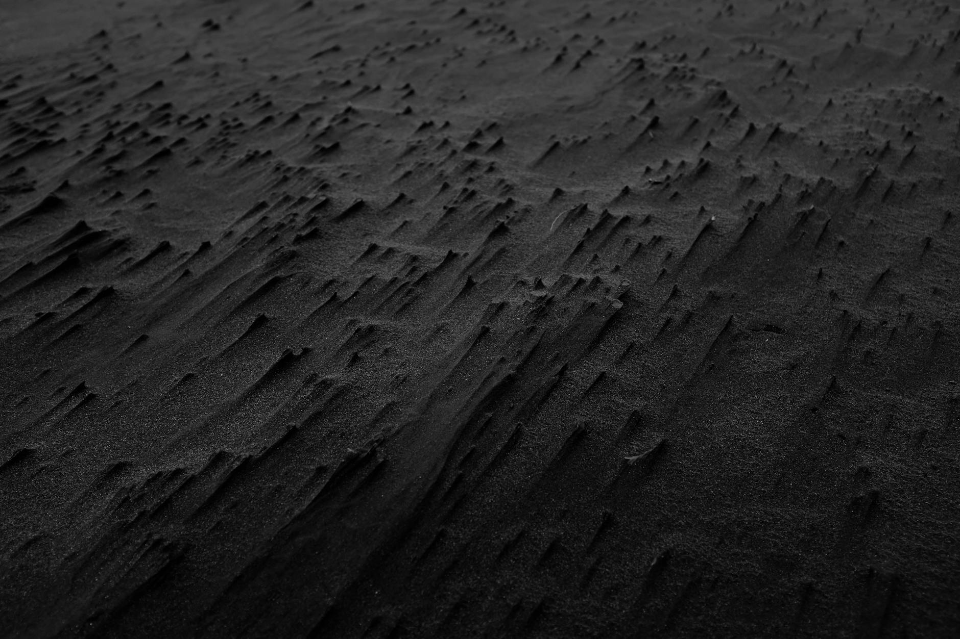 Close-up van zwarte zandstructuur met ribbels, als illustratie voor Moddervlekken op tapijt