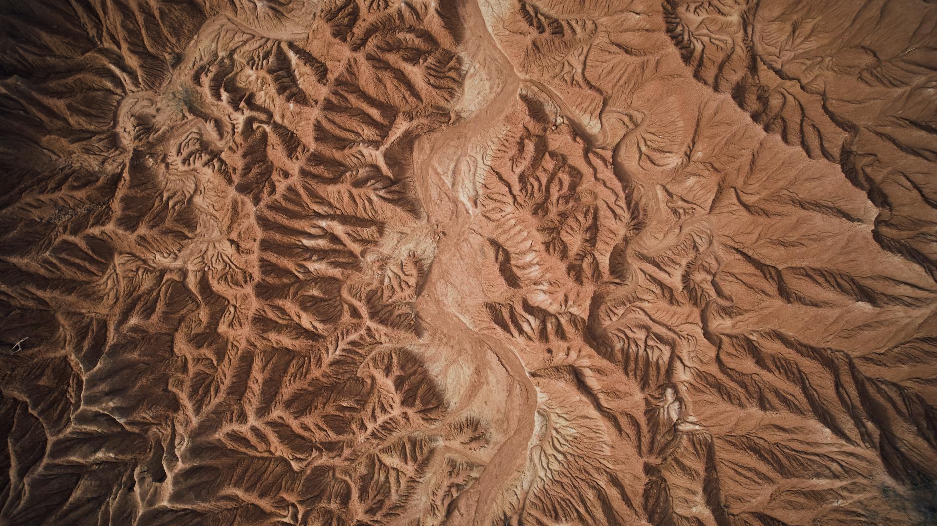 Aerial view of rugged desert landscape with deep canyons and rocky ridges.